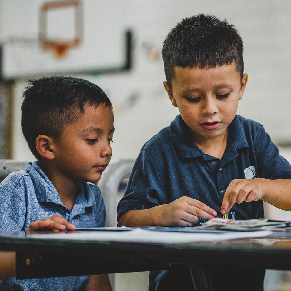 Two young boys sitting at a table working on an activity